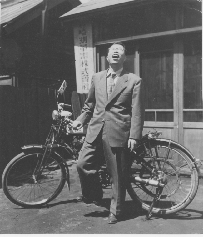 創業当時、モーター付き自転車で現場へ向かう、岩崎創業者 古口貞義の姿。